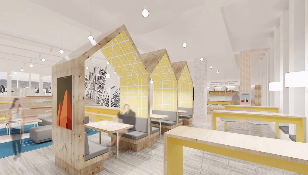 A modern, brightly lit cafe with wooden booths shaped like houses, yellow geometric panels, and gray seating—perfect for relaxing after viewing a nearby studio unit for sale. White walls display black-and-white artwork, while hanging lights and large windows brighten the space.
