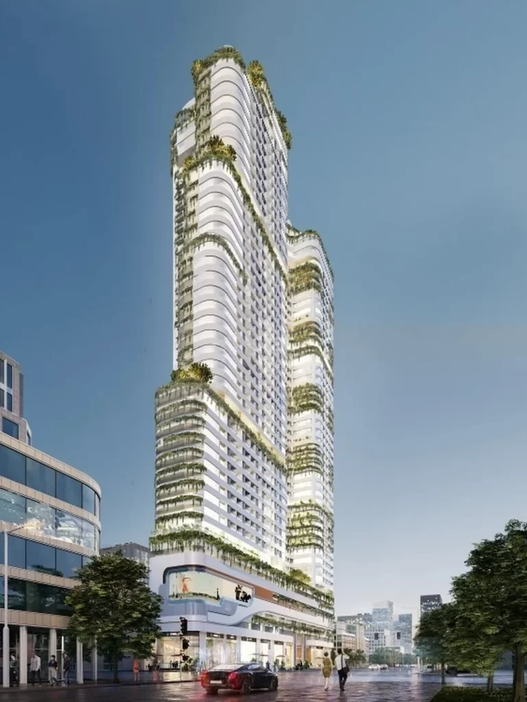 A modern high-rise building with multiple setbacks, white facade, and abundant greenery on terraces, features sleek studio apartment for rent; set against a clear sky with city buildings and a few people and cars at street level.