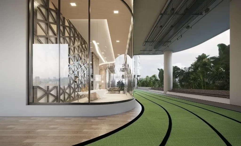 Modern studio apartment for rent featuring large curved glass windows overlooking a green running track, lush plants, and tall pillars supporting an overhang.