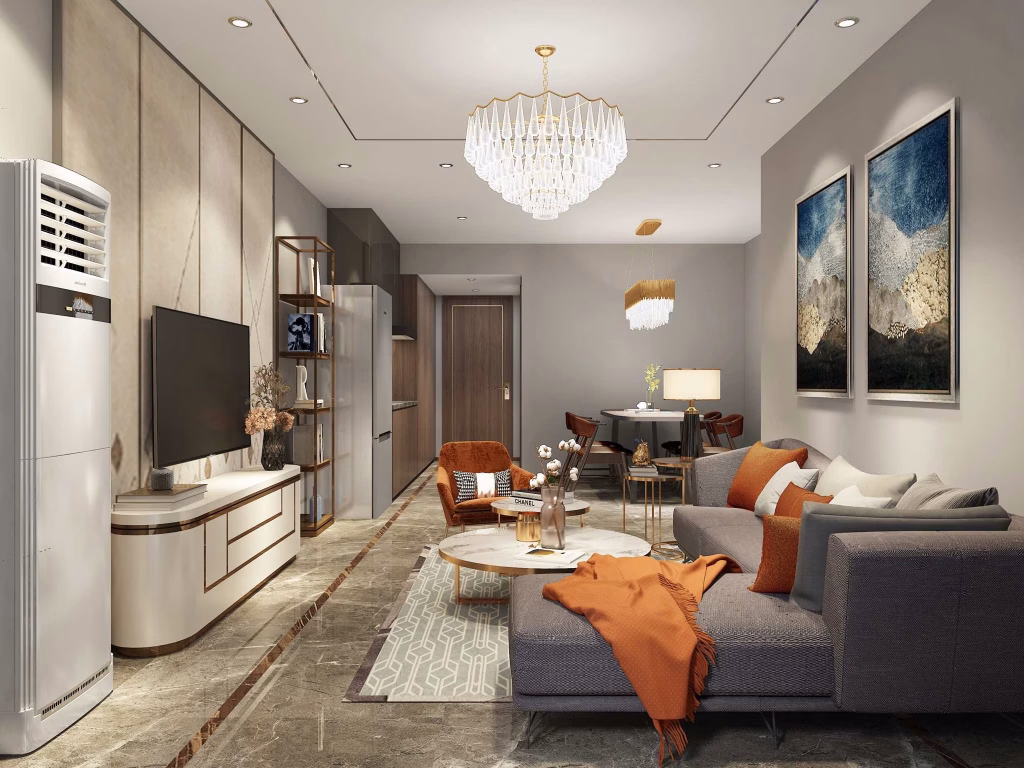 Modern living room with gray and orange decor in this Studio Unit For Sale, featuring a sectional sofa, coffee table, TV, chandelier, wall art, and dining area; kitchen appliances and a standing air conditioner are also visible.