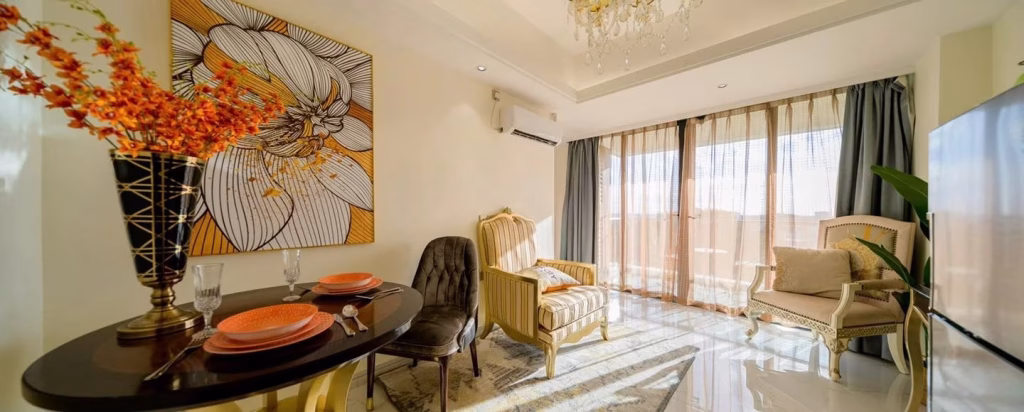 A bright, modern living room in Star City with large windows, elegant armchairs, a round dining table set for two, large floral wall art, and decorative plants. Sunlight streams in through sheer curtains.