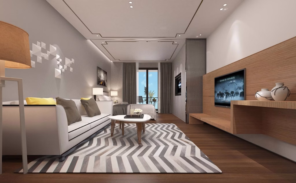 Modern living room at The Seagate Apartment featuring a white sofa, yellow and gray cushions, chevron rug, coffee table, and TV. Large window with curtains brings in natural light and offers tree views. Neutral palette with wood accents.