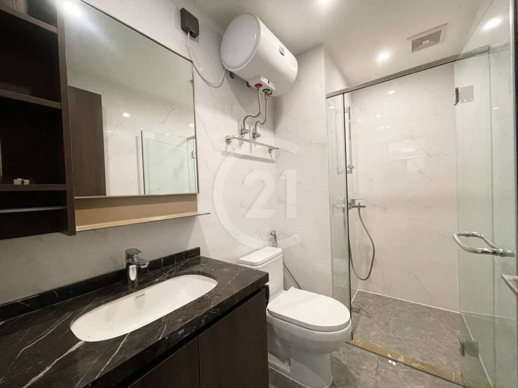 Modern bathroom with a black countertop sink, mirror, toilet, wall-mounted water heater, and a glass-enclosed shower area with marble-style tiles and a handheld showerhead.